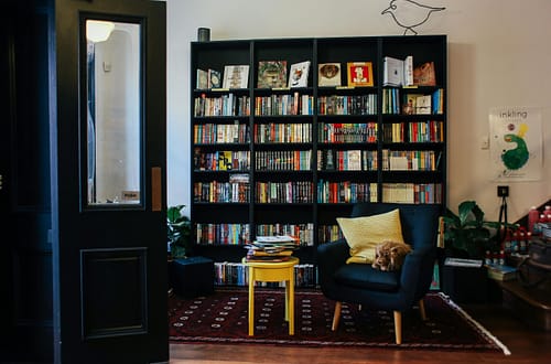 A warm and inviting home library featuring a bookshelf, cozy armchair, and decorative accents.