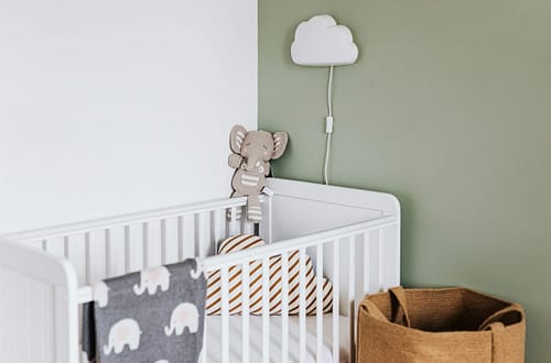 Modern baby room featuring a white crib, soft decor, and pastel accents.
