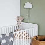 Modern baby room featuring a white crib, soft decor, and pastel accents.
